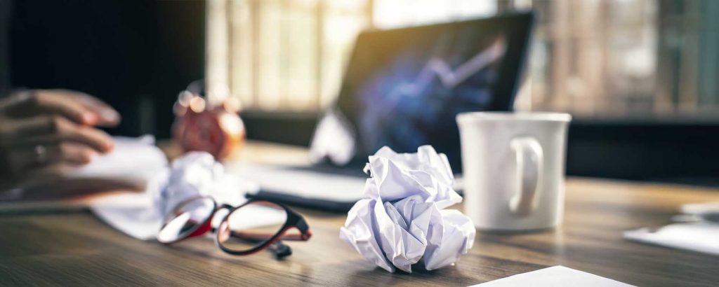 Mesa bagunçada com papéis amassados, simbolizando estresse no ambiente de trabalho relacionado à Lei da Saúde Mental