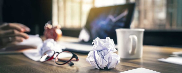 Mesa bagunçada com papéis amassados, simbolizando estresse no ambiente de trabalho relacionado à Lei da Saúde Mental