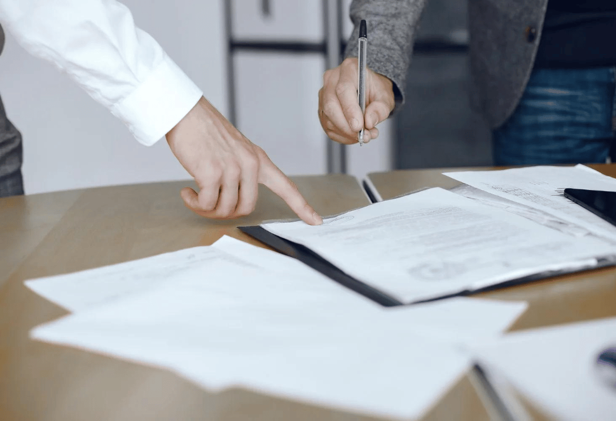 Pessoa apontando cláusula em contrato durante análise de documento na gestão condominial